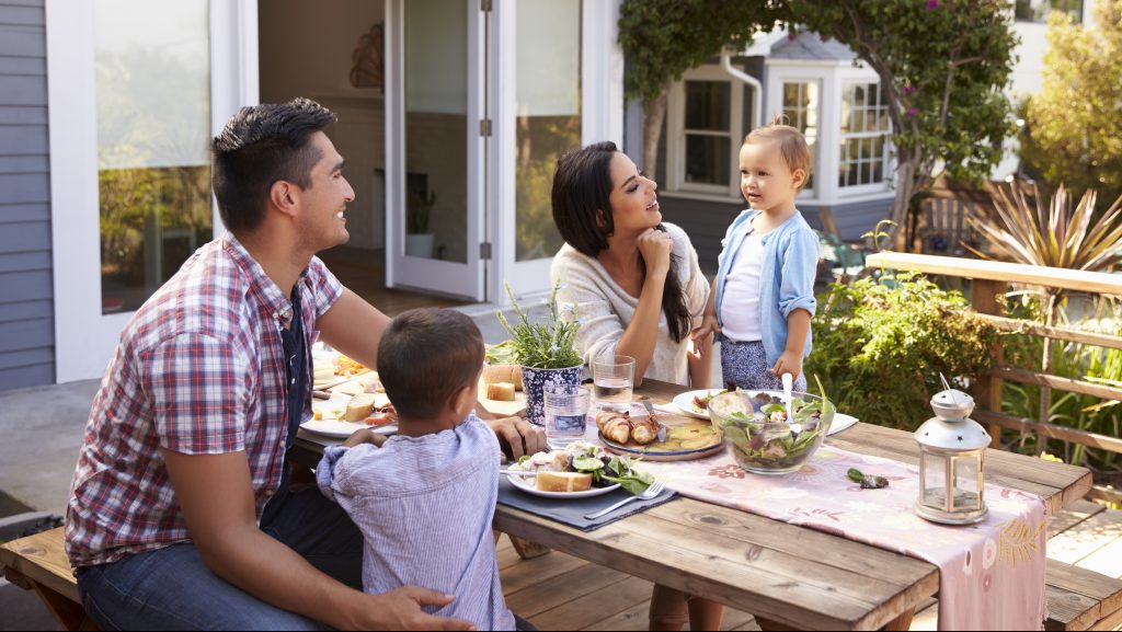 Family At Home Eating Outdoor Meal In Garden Together